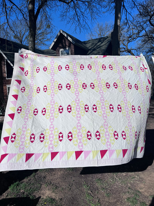 This lovely has white, red, pink and yellow, intricate triangles and hand quilting and stitching