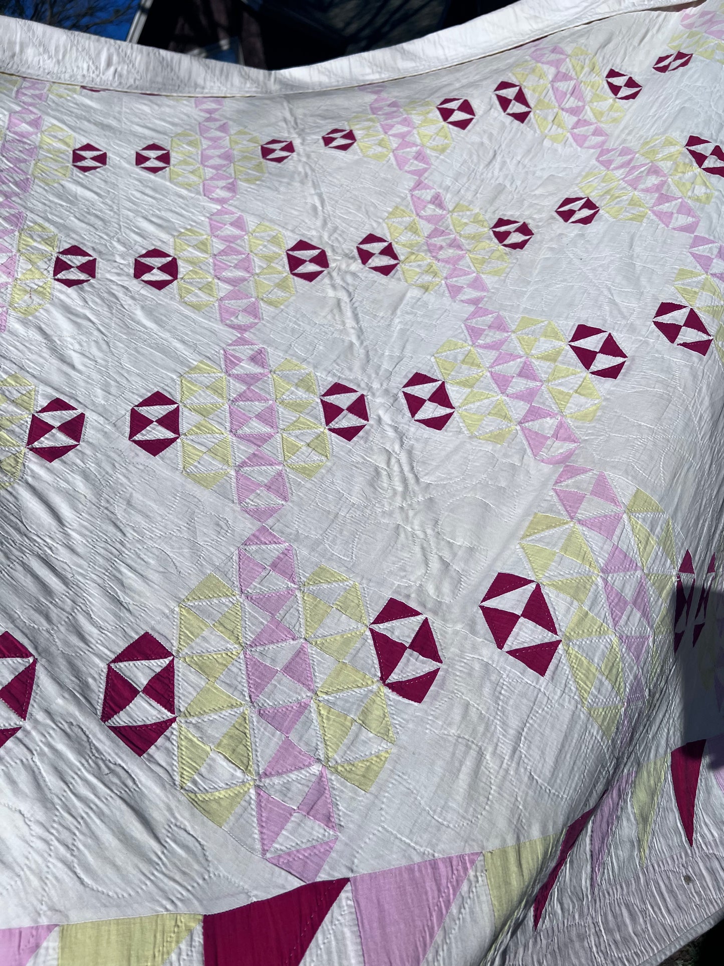 This lovely has white, red, pink and yellow, intricate triangles and hand quilting and stitching