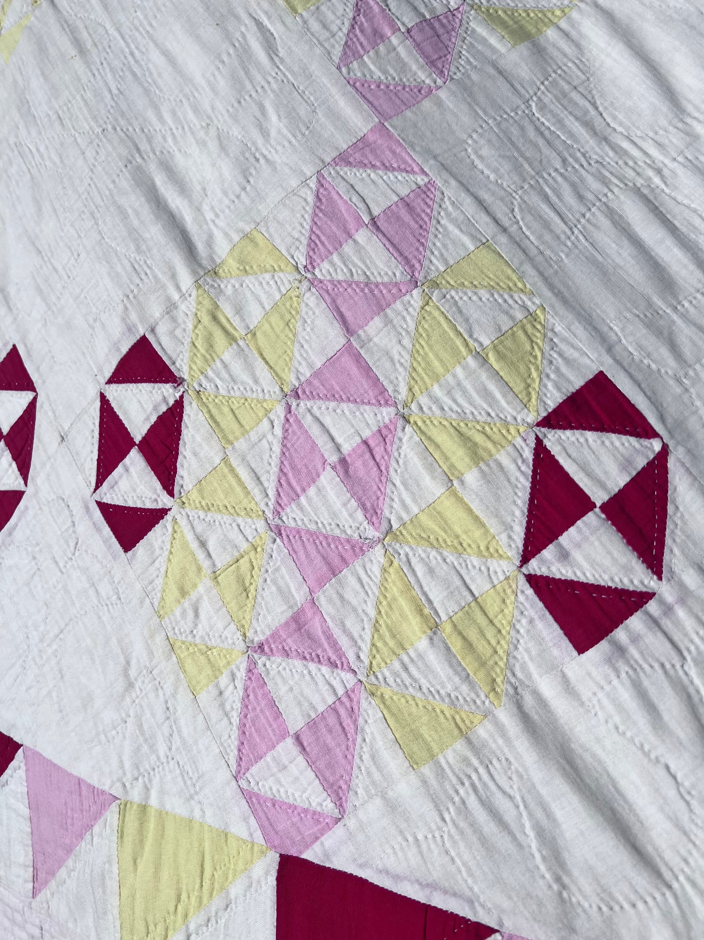 This lovely has white, red, pink and yellow, intricate triangles and hand quilting and stitching