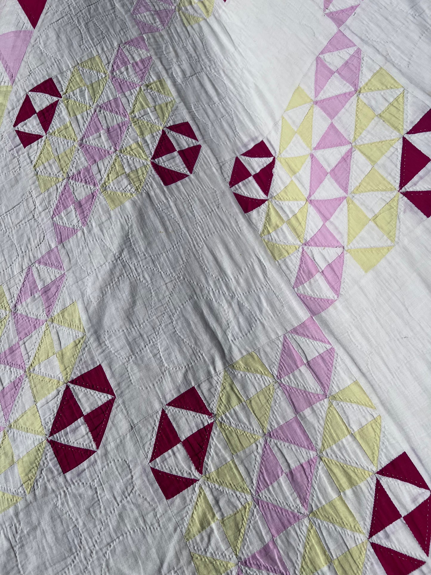 This lovely has white, red, pink and yellow, intricate triangles and hand quilting and stitching