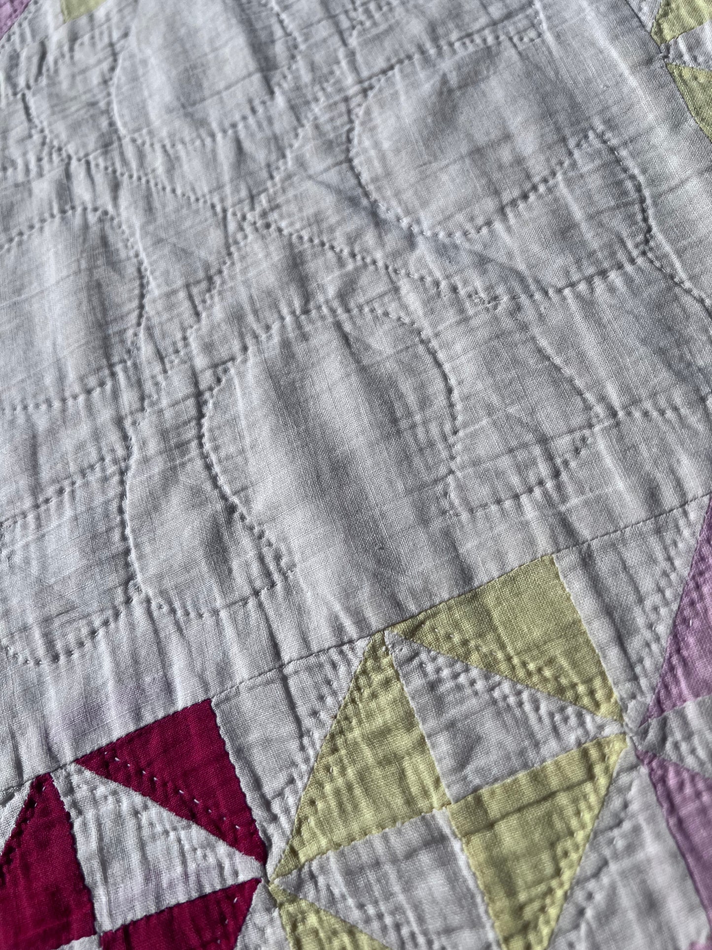 This lovely has white, red, pink and yellow, intricate triangles and hand quilting and stitching