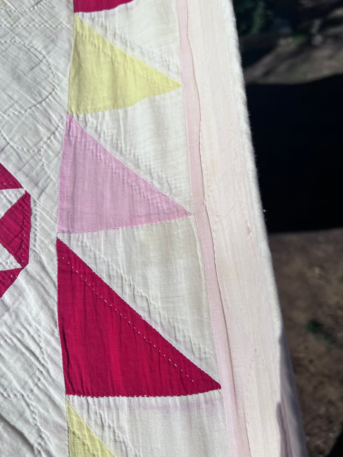 This lovely has white, red, pink and yellow, intricate triangles and hand quilting and stitching