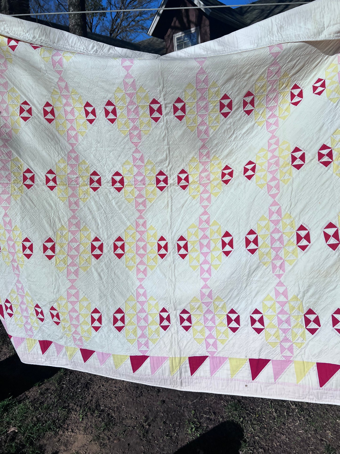 This lovely has white, red, pink and yellow, intricate triangles and hand quilting and stitching